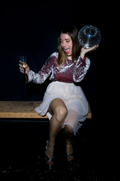 Mujer borracha sentada en un banco con bola de discoteca