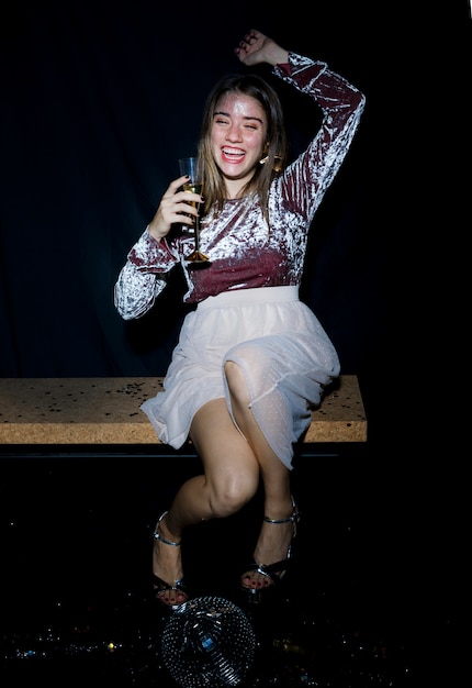 Mujer borracha sentada en un banco con copa de champán