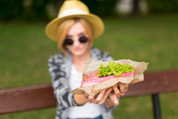 Mujer borrosa sosteniendo un sándwich fresco