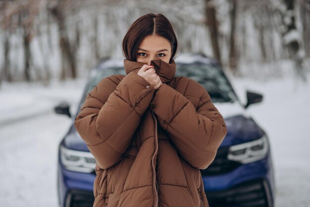 Mujer en el bosque de invierno por su coche