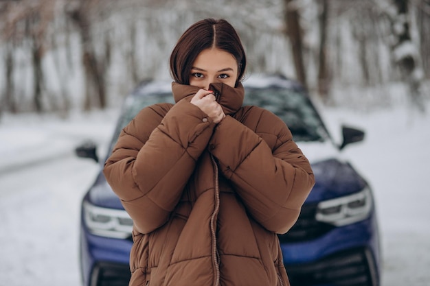 Mujer en el bosque de invierno por su coche