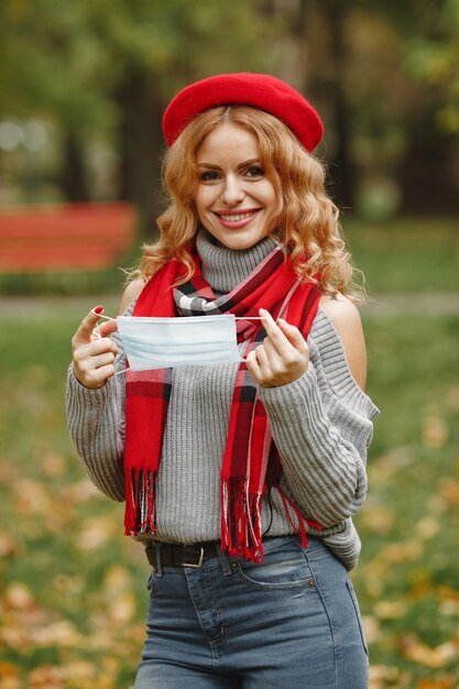 Mujer en bosque otoñal. Persona con máscara. Tema de coronavirus. Dama con un pañuelo rojo.