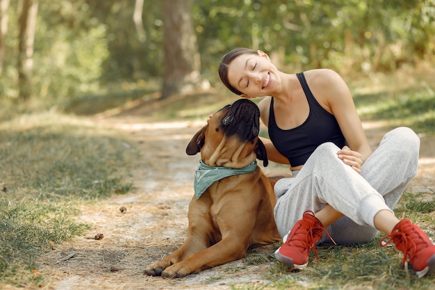 mujer en un bosque de verano jugando con perro