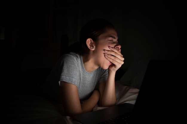 Mujer bostezando mientras trabajaba tarde en casa