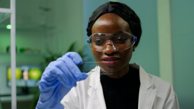 Mujer botánica africana mirando muestra de prueba genética para experimento biológico