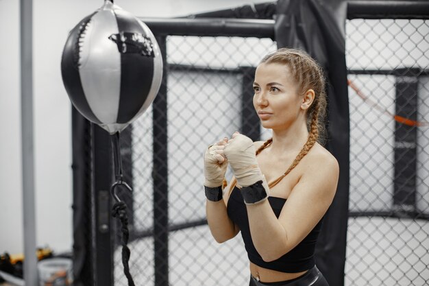 Mujer de boxeo. Principiante en un gimnasio. Dama en ropa deportiva negra.