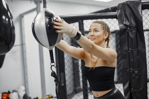 Mujer de boxeo. Principiante en un gimnasio. Dama en ropa deportiva negra.