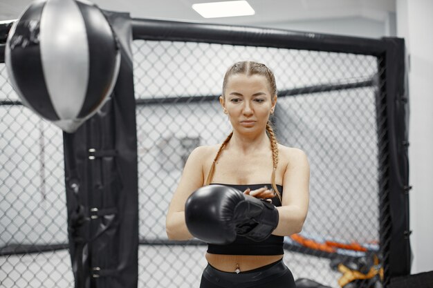 Mujer de boxeo. Principiante en un gimnasio. Dama en ropa deportiva negra.