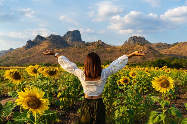 Mujer con los brazos levantados en el campo de girasol en kao jeen lae en  lopburi, tailandia | Foto Premium