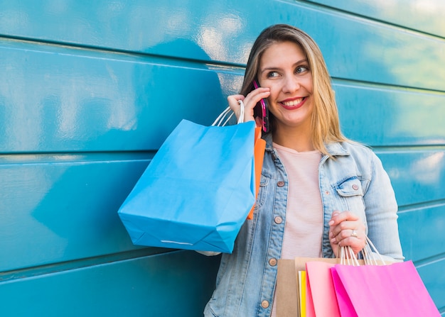 Mujer con brillantes bolsas de compras hablando por teléfono