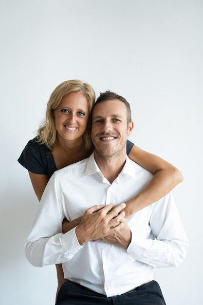 Mujer bronceada alegre que abraza al novio hermoso en la camisa blanca.