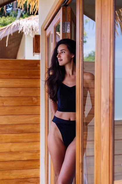 Mujer bronceada en forma caucásica vistiendo bikini vintage antiguo, posando en la villa del hotel de lujo