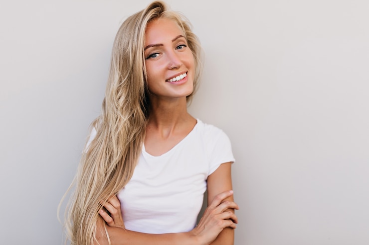 Foto gratuito mujer bronceada soñadora sonriendo. modelo de mujer con cabello rubio riendo a la cámara.