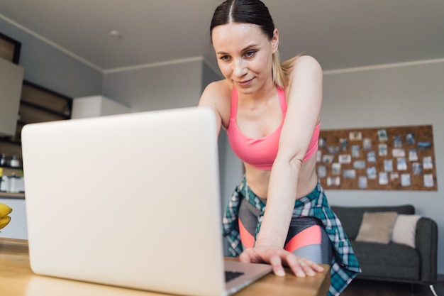 Mujer buscando lecciones de video deportivo en la computadora portátil