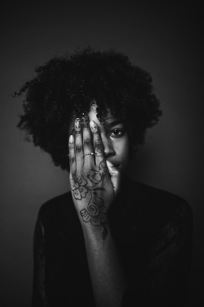 Foto gratuita mujer con cabello afro negro y tatuaje en su mano