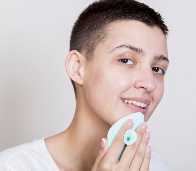 Foto gratuita mujer con cabello corto limpiando su rostro mientras mira a la cámara