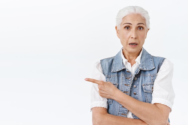 Foto gratuita mujer con cabello gris haciendo preguntas sobre el producto, boca abierta mientras habla con el dependiente se preguntaba levantar las cejas