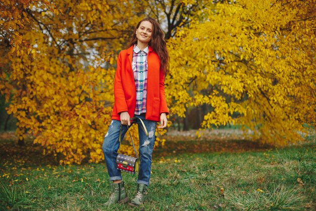 Mujer con cabello largo ondulado disfrutando de otoño en el parque.