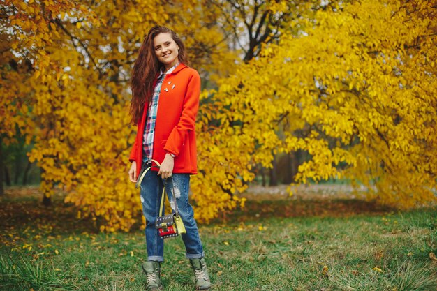 Mujer con cabello largo ondulado disfrutando de otoño en el parque.