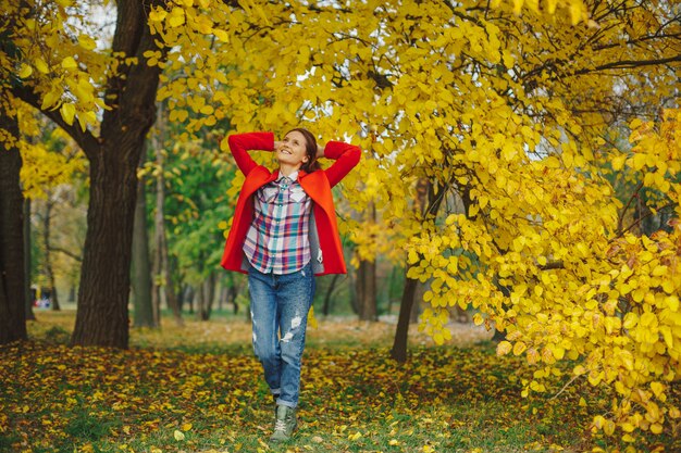 Mujer con cabello largo ondulado disfrutando de otoño en el parque.