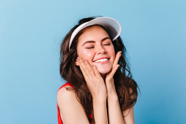 Mujer de cabello oscuro con sonrisa blanca como la nieve toca sus mejillas