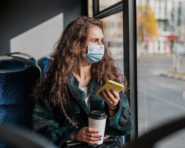 Foto gratuita mujer con cabello rizado sosteniendo café y teléfono móvil