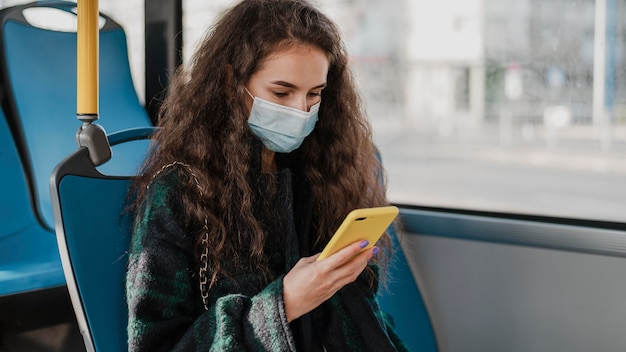 Mujer con cabello rizado usando su teléfono móvil en el autobús