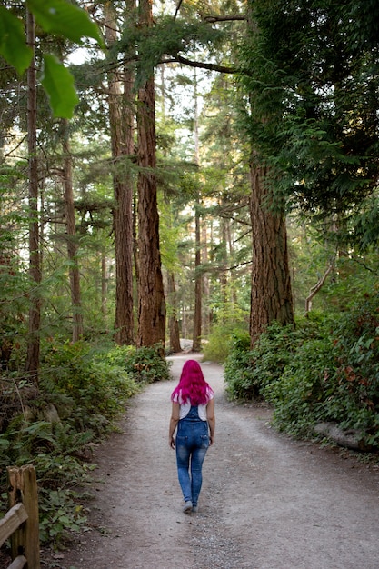 Foto gratuita mujer con cabello rosado caminando por el sendero en el bosque