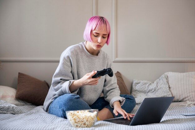 Mujer con cabello rosado jugando con un joystick en la computadora portátil