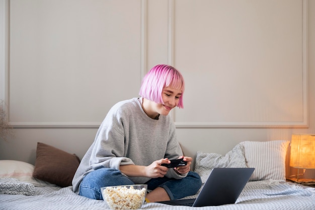 Mujer con cabello rosado jugando con un joystick en la computadora portátil