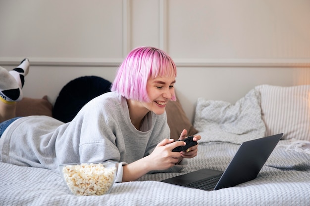 Mujer con cabello rosado jugando con un joystick en la computadora portátil