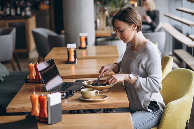 Mujer en un café almorzando y hablando por teléfono