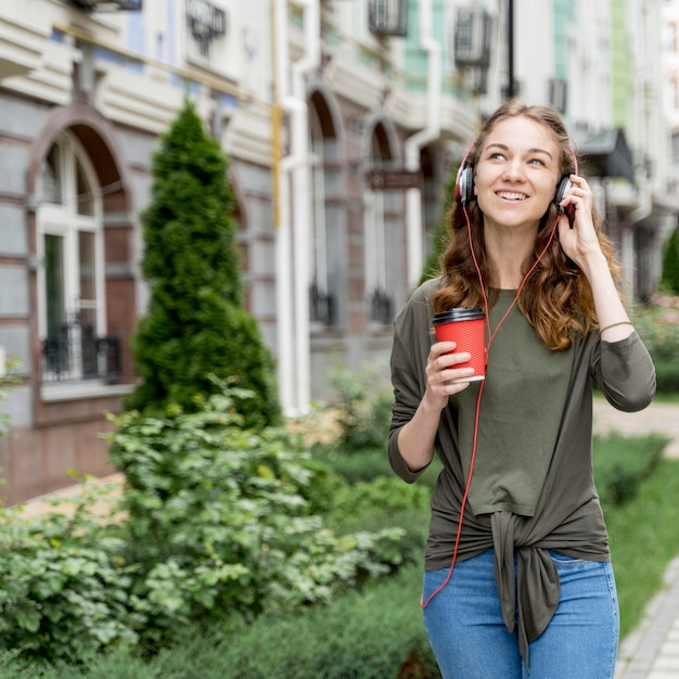 Mujer con café y auriculares.