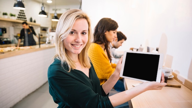 Mujer en café que muestra la pantalla de la tableta