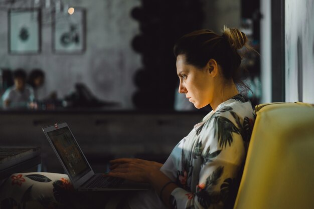 mujer en un café que trabaja detrás de una computadora portátil