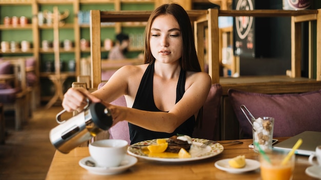 Mujer en el café que vierte el café en la taza