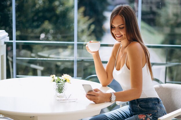 Mujer en café tomando café y hablando por teléfono