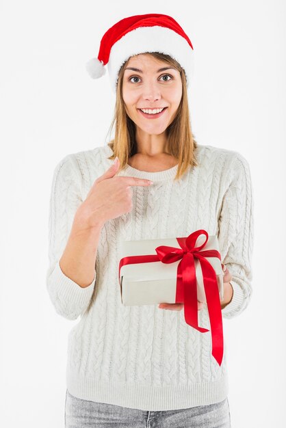 Mujer con caja de regalo apuntando el dedo a sí misma