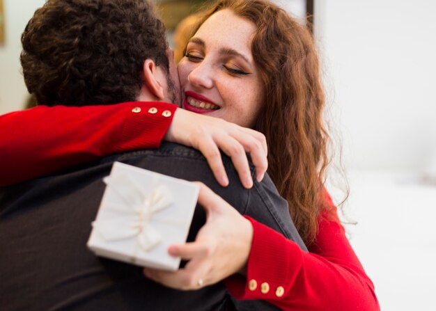 Mujer con caja de regalo pequeña abrazando hombre