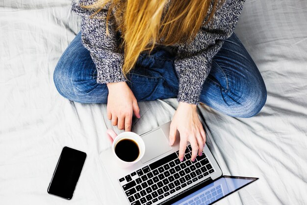 Mujer en cama con laptop y café