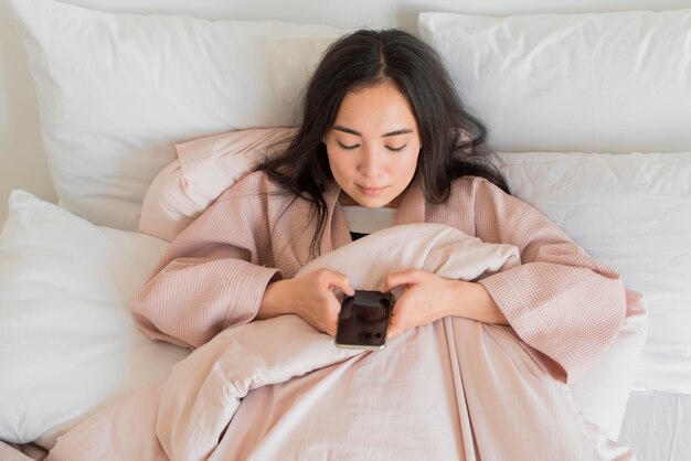 Mujer en cama con móvil