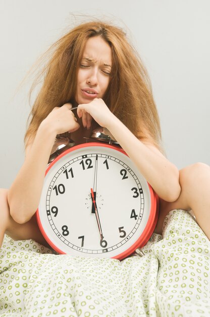 Mujer en la cama con reloj despertador