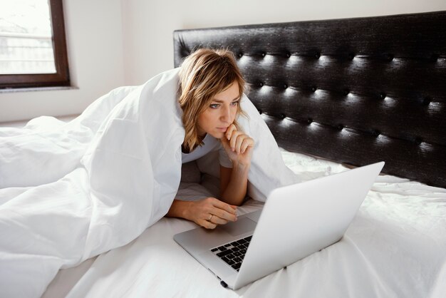 Mujer, en cama, usar la computadora portátil