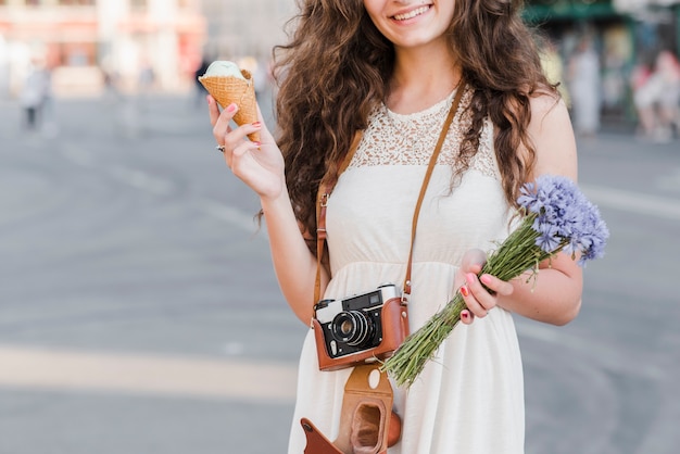 Foto gratuita mujer con cámara y helado en la calle