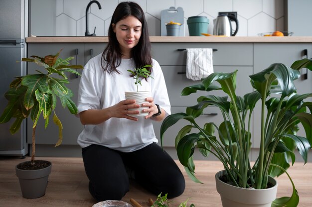 Mujer cambiando las macetas de sus plantas en casa durante la cuarentena