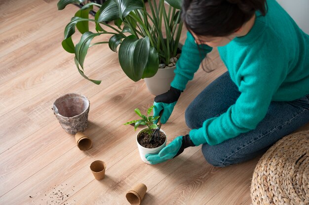 Mujer cambiando las macetas de sus plantas en casa durante la cuarentena