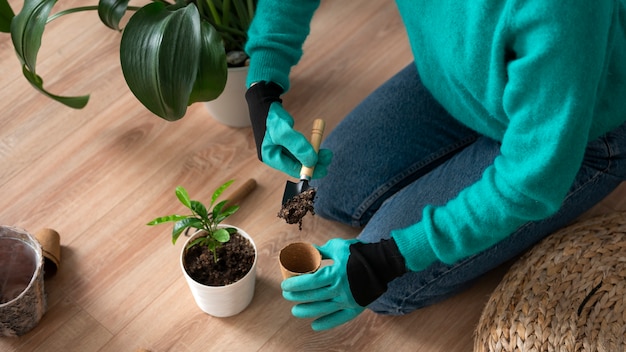 Mujer cambiando las macetas de sus plantas en casa durante la cuarentena