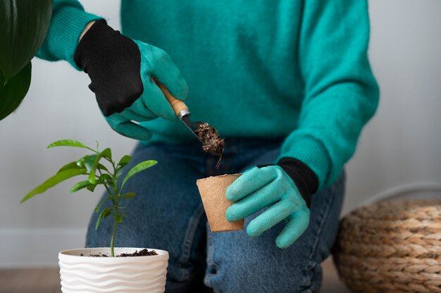 Mujer cambiando las macetas de sus plantas en casa durante la cuarentena