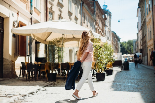 La mujer camina antes del café de la calle