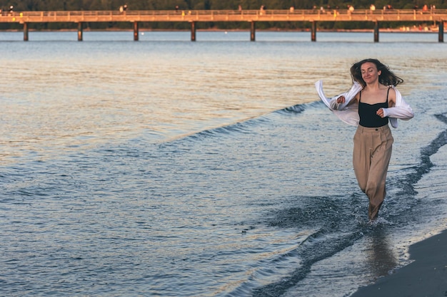 Una mujer camina descalza por el mar en el espacio de la copia al atardecer